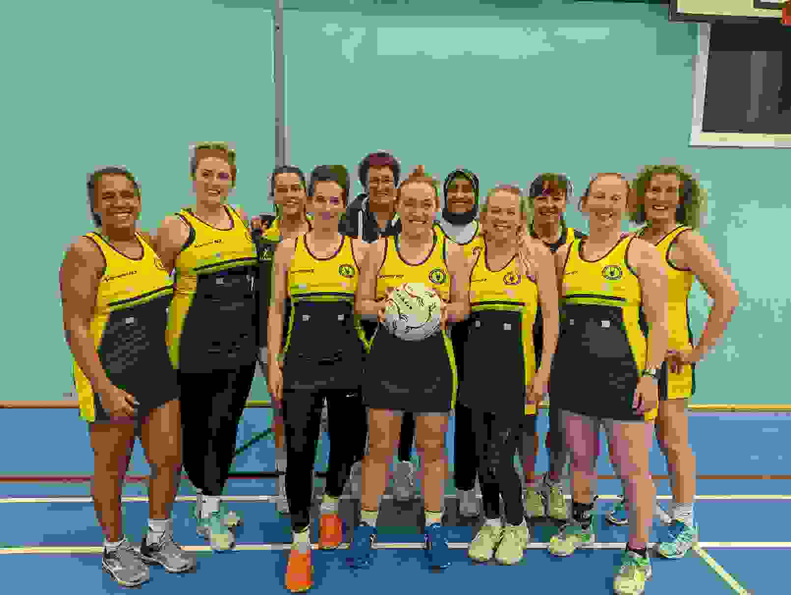 Kate and her netball team. Kate is standing in the middle of the smiling group, holding the ball.