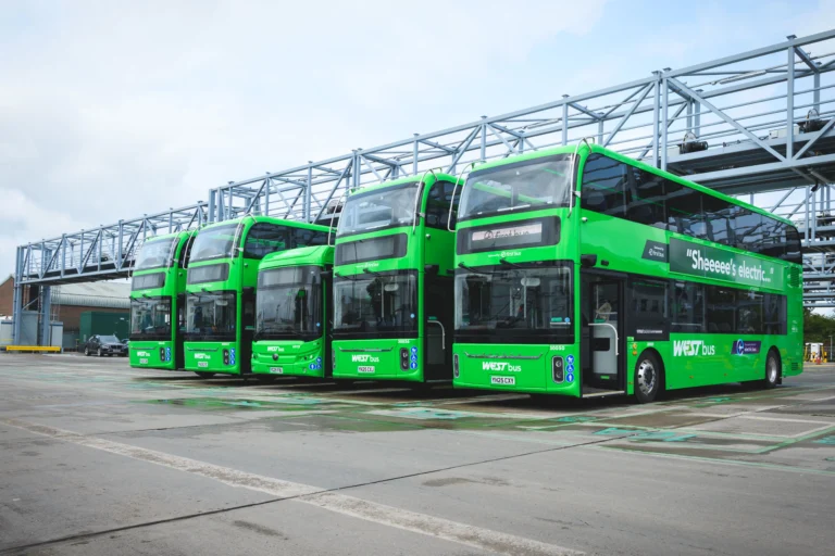 A row of five electric buses are parked under a charging gantry at First Bus' Hengrove depot